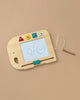 The Wooden Elephant Magic Drawing Board is a creative toy for children, featuring colorful geometric buttons along with a scribble pad and magnetic pen attached by a string. It is displayed on a beige background.