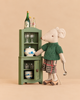 A Maileg Grandma’s China Cabinet Set featuring a Grandma Mouse in a green sweater and plaid skirt standing beside a miniature green china cabinet filled with tiny dishes, bottles, and a metal ladle.