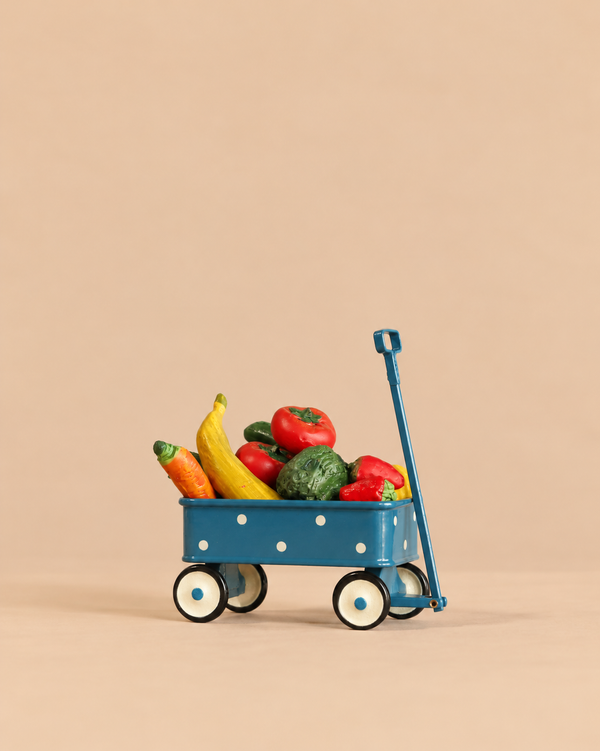 A blue miniature Maileg Grocery Wagon Set with white polka dots, filled with assorted fruits and veggies including a banana, carrot, and peppers.
