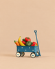 A blue miniature Maileg Grocery Wagon Set with white polka dots, filled with assorted fruits and veggies including a banana, carrot, and peppers.