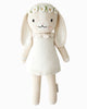 Cuddle + Kind Hannah the Bunny is a cream-colored hand-knit bunny doll with long floppy ears, dressed in a white dress and daisy flower crown. Made from premium cotton yarn, this fair trade bunny has black eyes, pink cheeks, and a sweet smile.