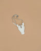 The Donsje Leather Blinc Purse - Unicorn is a small white purse with a silver glittery horn and adjustable leather strap, shown on a plain light brown background.