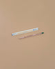 A pregnancy test and a Tomatoes Plantable Pencil – Eco-Friendly with a green eraser are placed on a plain beige surface. The pencil, ideal for growing cherry tomatoes, sits below the pregnancy test.