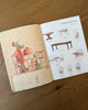 An open page of Odin Parker’s Maileg Catalog featuring a mouse illustration serving cake at a table, alongside various toy dining tables and chairs with product codes.