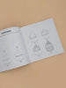An open copy of "All the Things: How To Draw Books For Kids" rests on a beige surface, displaying step-by-step cupcake drawing instructions, from basic shapes to a finished treat—ideal for simple drawing lessons.