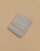 The Maileg Baby Blanket, in a light gray ribbed knit, is folded and displayed on a plain beige background, exuding the warmth and coziness of a comforting blanket.