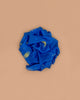 Sarah's Silks Giant Playsilk - Starry Night, a crumpled blue silk with gold stars, crescent moon, and ringed planet designs, rests on a plain beige background—ideal for imaginative play and open-ended fun.