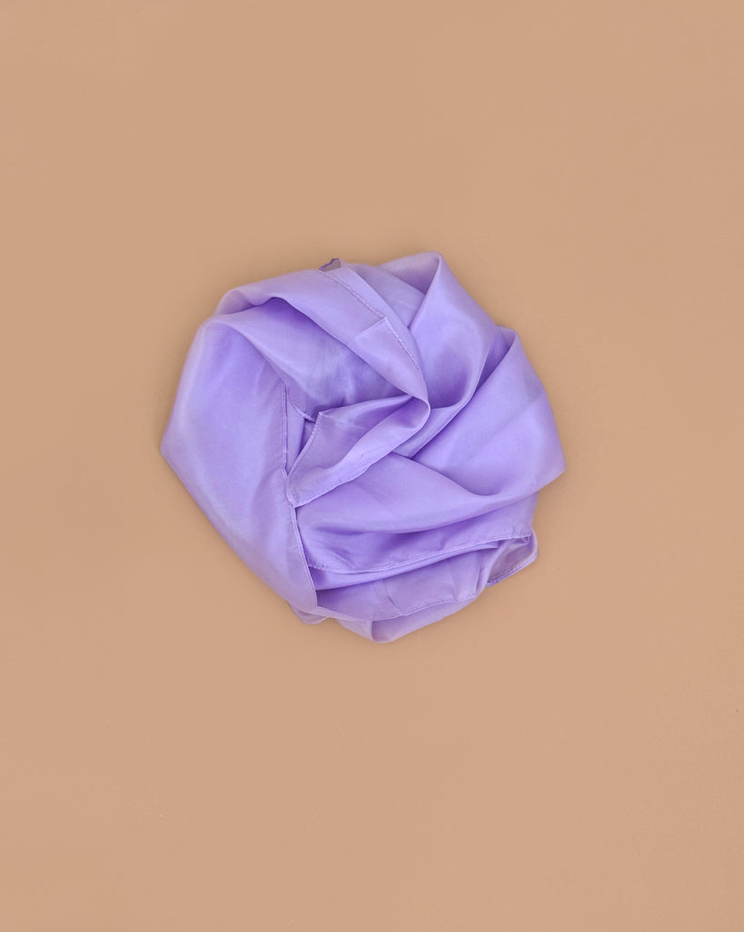 Sarah's Silks Solid Color Playsilk in Lavender, inspired by Playsilks, is displayed in a circular arrangement on a plain beige background.