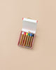 An open box of Kitpas Crayons - 6 Colors sits on a plain beige background. The six thick, non-toxic crayons have brown paper wrappers and are in a white box with red edges.
