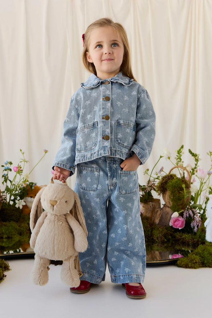 A young girl in a denim jacket and jeans holding a hazelnut Snuggle Bunnies - Penelope Backpack with an adjustable-strap plush bunny design.