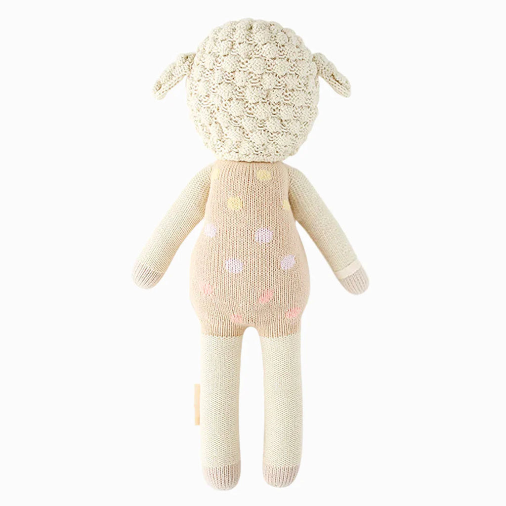 Cuddle + Kind Lucy the Lamb is a hypoallergenic stuffed animal in cream and beige with small pastel polka dots on its back, shown from behind. It features a textured head and floppy ears for extra charm.