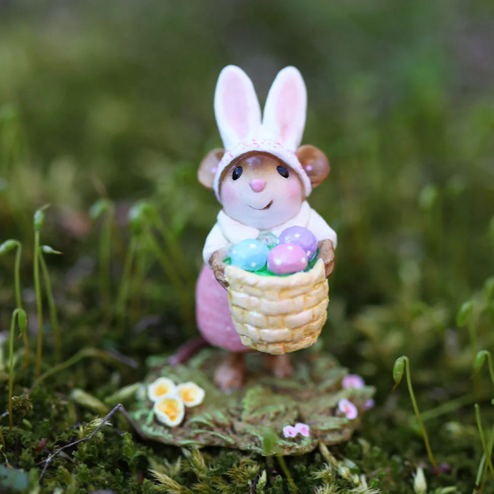 The Wee Forest Folk Tiny Collectible - Hoppy Easter Girl features a hand-sculpted mouse in bunny ears and a pink dress, holding a basket of pastel eggs on a green patch with yellow flowers and moss.