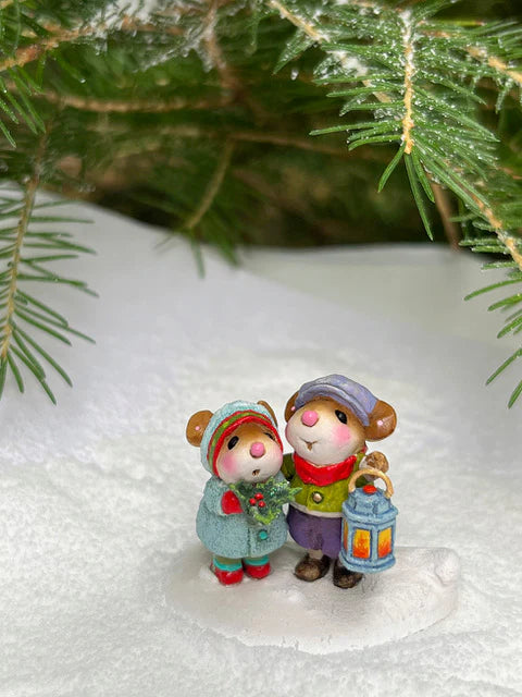 Two hand-sculpted Wee Forest Folk Tiny Collectible mice—The Little Wanderers—stand on snow under pine branches; one holds a blue lantern, and the other wears a teal coat and red scarf.