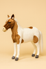 The Large Pony Stuffed Animal, 42'' - FINAL SALE, features brown and white patches, a white mane and tail, and gray hooves. This realistic plush by HANSA stands upright against a plain beige background and is expertly hand sewn.