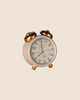 A small, vintage-style alarm clock with gold bells and legs, a white body, and black hands sits against a plain beige background—an adorable piece from the Maileg Suitcasa Furnished Set, perfect for enhancing your Maileg dollhouse or complementing your Maileg mouse furniture.