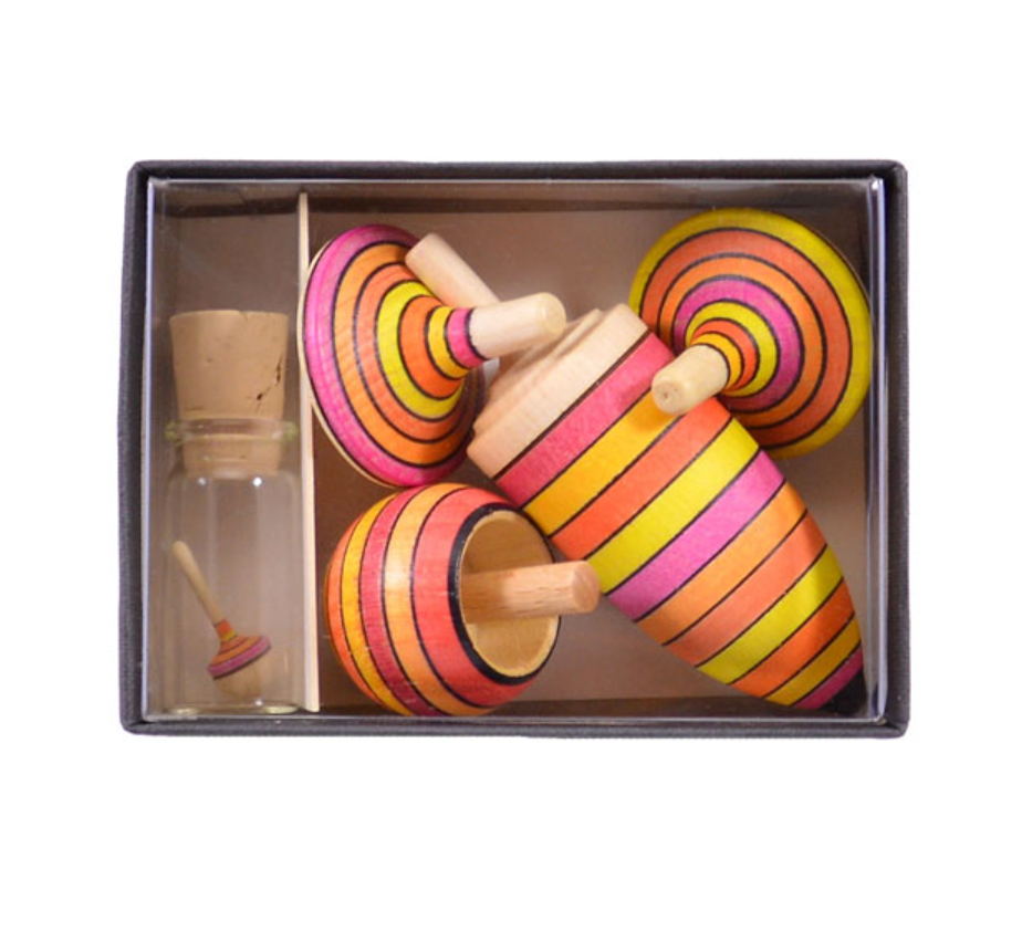 The Mader Spinning Top Champion Learning Set - Fire includes four colorful striped tops in assorted sizes and a small glass bottle with a cork lid containing a miniature top, all made to meet toy safety standards.