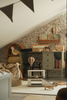 A cozy attic children's room with floral wallpaper, a green desk full of books, a black chair, stuffed toys, a Hot Air Balloon - Light Brown / Dark Brown hanging from the ceiling, and a soft beige bean bag under the sloped roof.