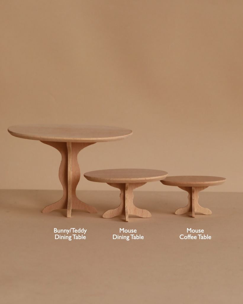 Three small wooden tables stand against a beige background, showcasing their quality. The largest is the Maileg Oval Dining Table, Miniature - Bunny/Rabbit Size, accompanied by the Mouse Dining Table and Mouse Coffee Table.