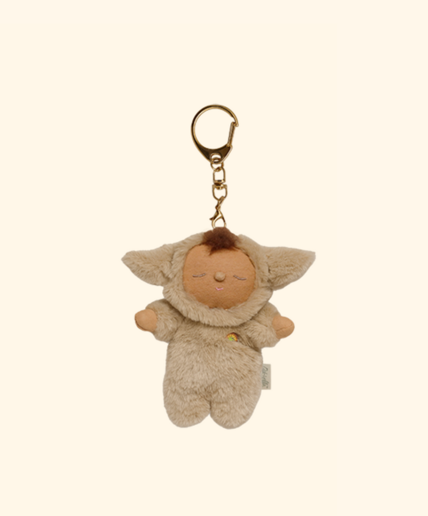 The Olli Ella Cozy Bag Charm - Lamby Pip is a plush bag accessory featuring a small, tan Cozy Dinkum doll with closed eyes and floppy ears dressed in a furry lamb costume, shown against a plain beige background.