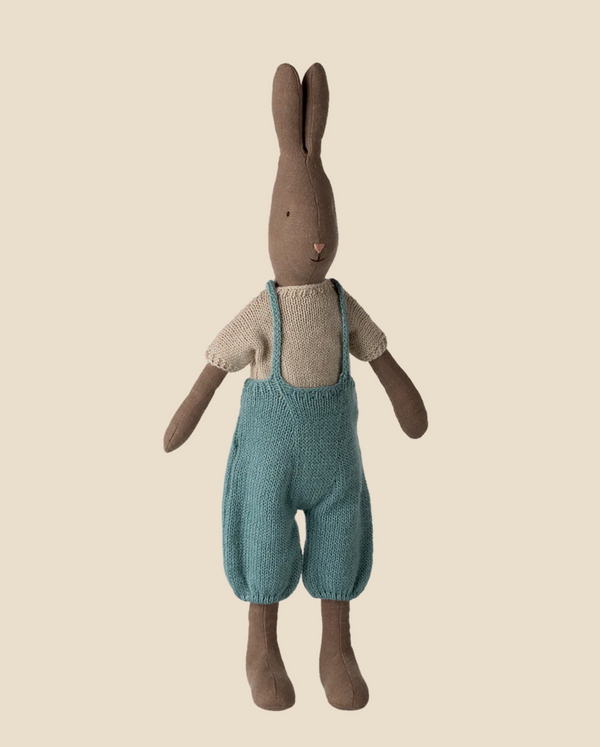The Pre-order: Maileg Rabbit, Size 3 - Brown, wears a knitted shirt and overall and stands upright against a plain light beige background.