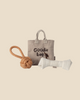 A beige fabric "Goodie bag" labeled Pre-order: Maileg Pet Supply, Toys (Expected arrival: 03/15/26) sits on a neutral background with a tan knotted rope ball and a white bone-shaped chew toy arranged in front.