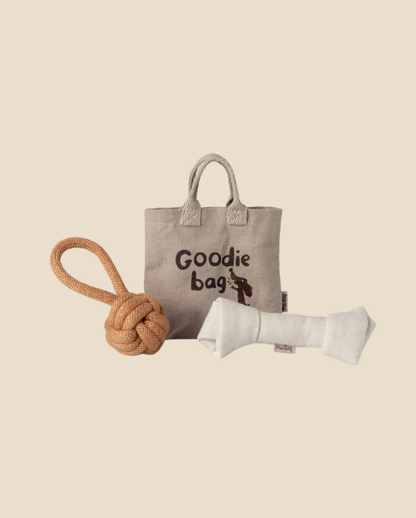 A beige fabric "Goodie bag" labeled Pre-order: Maileg Pet Supply, Toys (Expected arrival: 03/15/26) sits on a neutral background with a tan knotted rope ball and a white bone-shaped chew toy arranged in front.