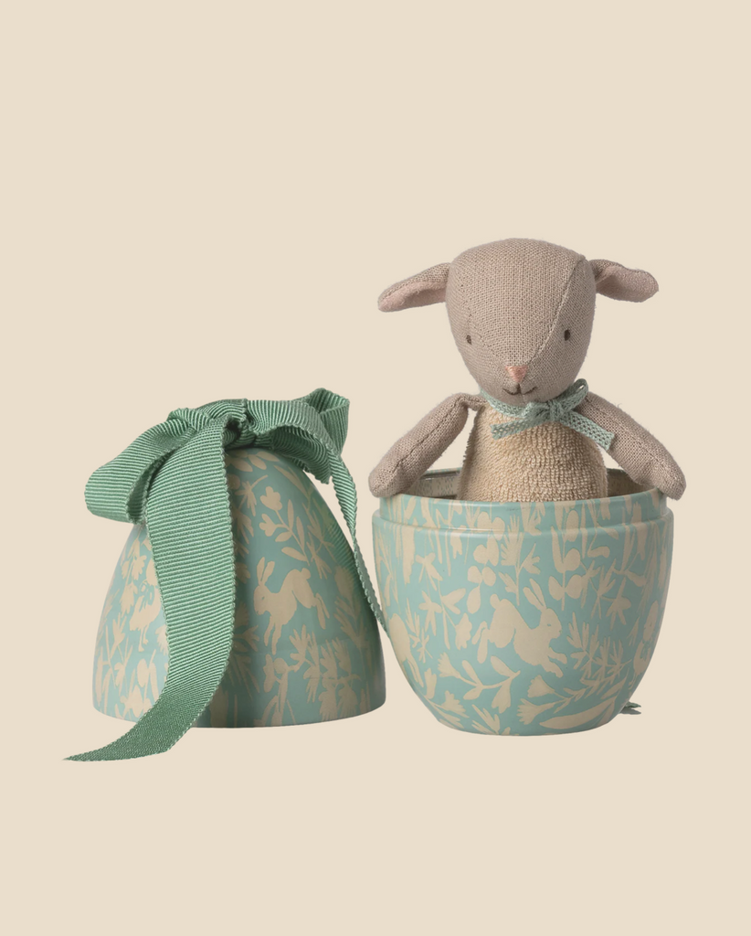 The Pre-order: Maileg Easter Egg with Micro Lamb, Small - Dusty Mint (arriving 02/15/26) features a micro lamb stuffed animal in a decorative dusty mint egg-shaped box with floral patterns and a green ribbon lid on a beige background.