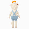 Cuddle + Kind Sebastian the Lamb is a hand-knit doll in light blue crisscross overalls and an orange crown, seen from the back. Made using sustainable fair trade practices. Background is plain white.