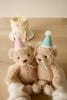 Two plush Snuggle Bunnies – Birthday Arthur and Fairy – wear pastel party hats as they're held together by gloved hands. A birthday cake with a candle sits behind them, making this the perfect keepsake gift for any special birthday bunny.