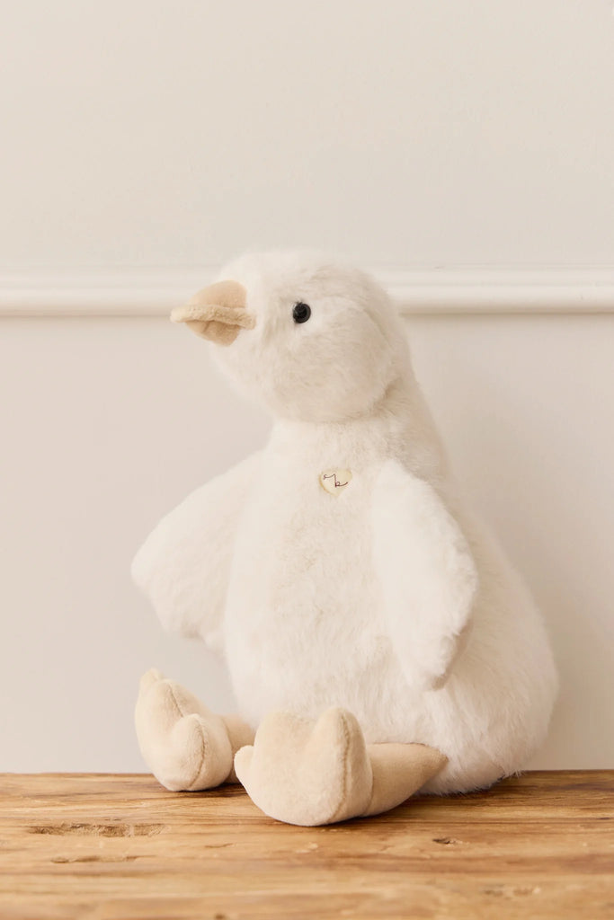 Snuggle Bunnies - Rose The Duck is a plush white duck toy with a beige beak and feet, made from super soft fabric, displayed on a wooden surface against a plain white background.
