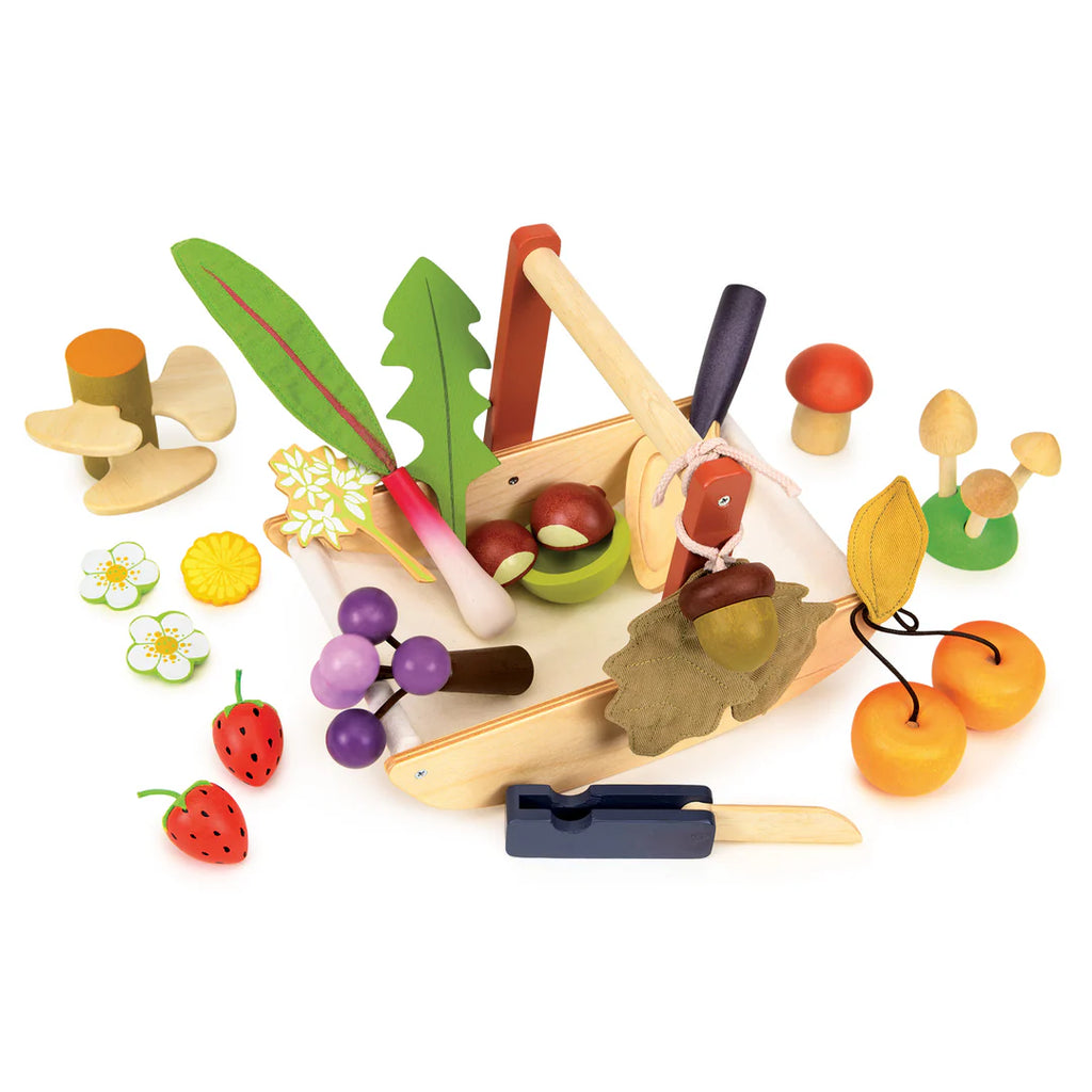 The Wild Wood Foraging Trug playset features a basket of toy fruits and vegetables, including cherries and mushrooms, along with a wooden knife. Create imaginative dishes using foraged plants around the basket with the included recipe leaflet.