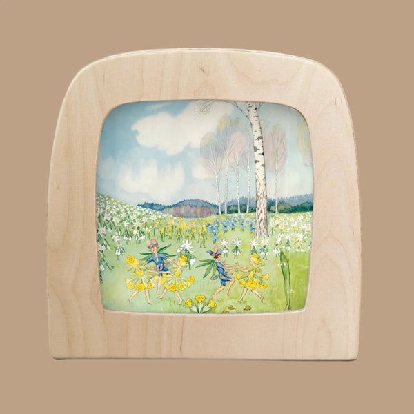 The Silhouette Only - Around The Year (May) for Toverlux Lamp showcases fairies dancing among yellow and white flowers, backed by birch trees and a cloudy sky in a magical, pastoral setting.