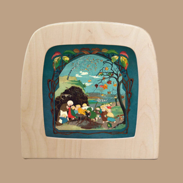 The Story of the Root Children Silhouette - Autumn for Toverlux Lamp highlights an intricate, colorful scene with people, a river, trees, and sky. Framed by leaves and branches in wooden craftsmanship magic silhouettes, it brings an enchanting touch to any space.