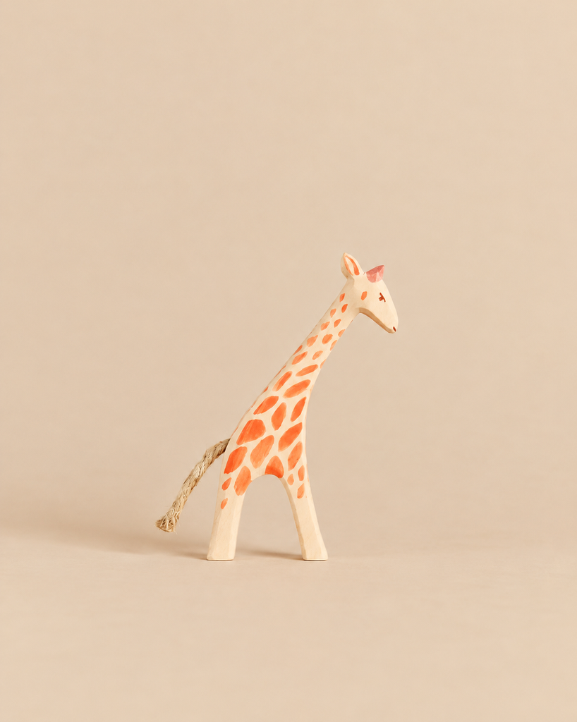 Ostheimer Small Giraffe - Head Low, a handcrafted wooden toy with orange spots and a rope tail, positioned with its head lowered for imaginative play.