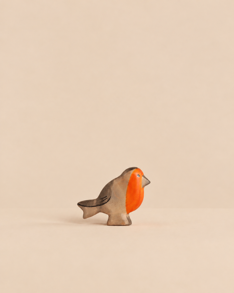 A small, sustainable Handmade Holzwald Bird - Redbreast wooden figurine with a painted orange breast.