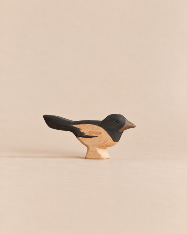Handmade Holzwald Bird - Magpie, a hand-carved wooden figurine for imaginative play with a black head and tail and a natural wood belly.