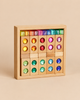 A wooden storage tray filled with a Bauspiel Gem Blocks with Lucent Cubes, 45-Piece Set, featuring construction blocks inlaid with colorful, faceted gemstones and topped by a row of small, translucent cubes.