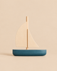 Sabo Concept Sailboat: a small wooden toy with a blue hull and light-colored sails, perfect for imaginative play.
