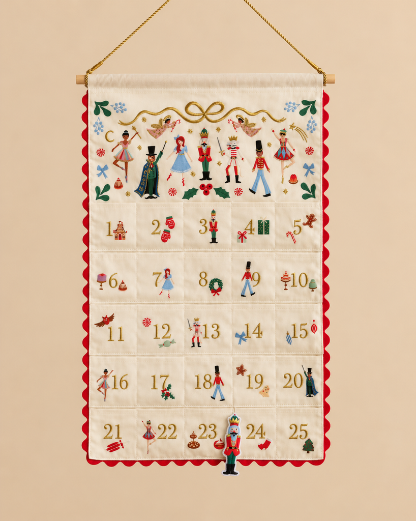 Nutcracker Embroidered Hanging Advent Calendar - Red featuring embroidered designs, numbered pockets, and a dangling Nutcracker figurine ornament at the number 24 pocket.