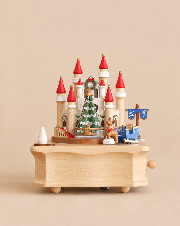 A Christmas Castle Music Box featuring a castle with red-roofed towers, a decorated Christmas tree in the center, and a reindeer pulling a blue sleigh.