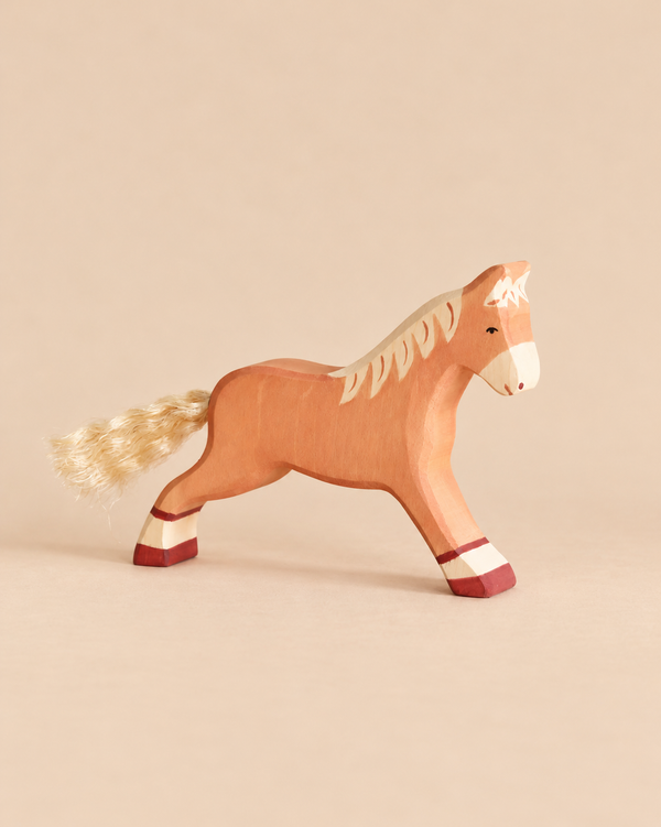 A handcrafted Holztiger Horse, Running, Light Brown figurine in a running pose, featuring painted hooves and a fiber tail.