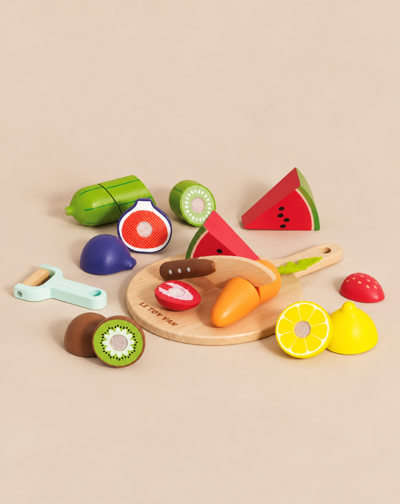 A Wooden Chopping Board & Sliceable Play Food set with a toy knife, surrounded by various pieces of sliced wooden play food.