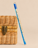 A clear liquid-filled Konges Sloejd Magical Glitter Wand - Rocket containing blue sequins and rocket-shaped glitter, leaning against a woven basket.