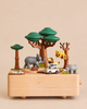 Wooden Safari Music Box featuring a hand-cranked safari scene with a white toy vehicle, a lion, an elephant, a leopard in a tree, and a rhinoceros.