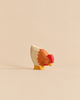 A small, handmade wooden chicken figurine from the Handmade Holzwald Farm Animals Set, painted in shades of cream, orange, and red.