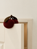 A cherry-shaped Konges Sloejd Door Stopper - Cherry made of silicone resting on the top edge of an open door.