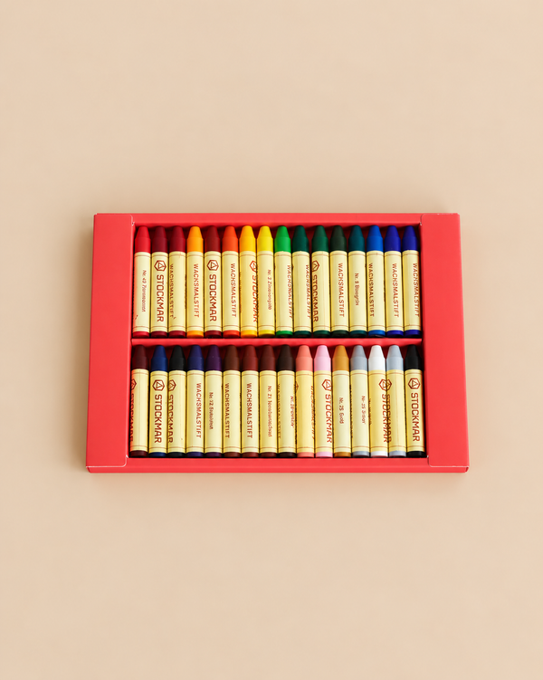 A Stockmar Wax Stick Crayons Box - 32 Assorted is a red box containing two rows of vibrant wax crayons arranged by color.