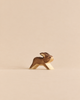 A small, minimalist wooden rabbit figurine from the Handmade Holzwald Woodland Animals Set in a running pose.