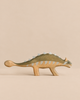 A handmade Holzwald Dinosaur Set ankylosaurus toy with a dark green back and pale grey plates along its spine.