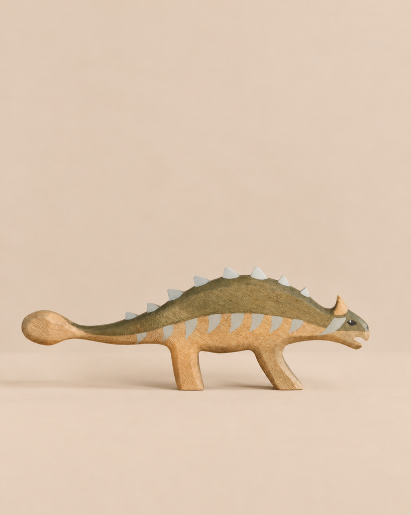 A handmade Holzwald Dinosaur Set ankylosaurus toy with a dark green back and pale grey plates along its spine.